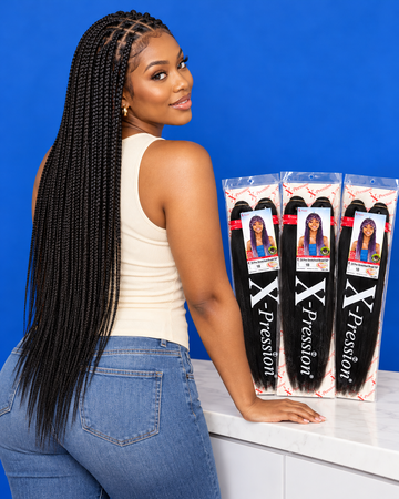 Woman with fresh mid-back knotless braids next to packs of 3X Pre-Stretched Braid 50" from Mary Queen Trade
